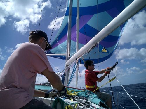 We use lots of little ropes to adjust the spinnaker sail. You can also see the St Lucia flag flotting. (St Lucia channel, Caribbean)